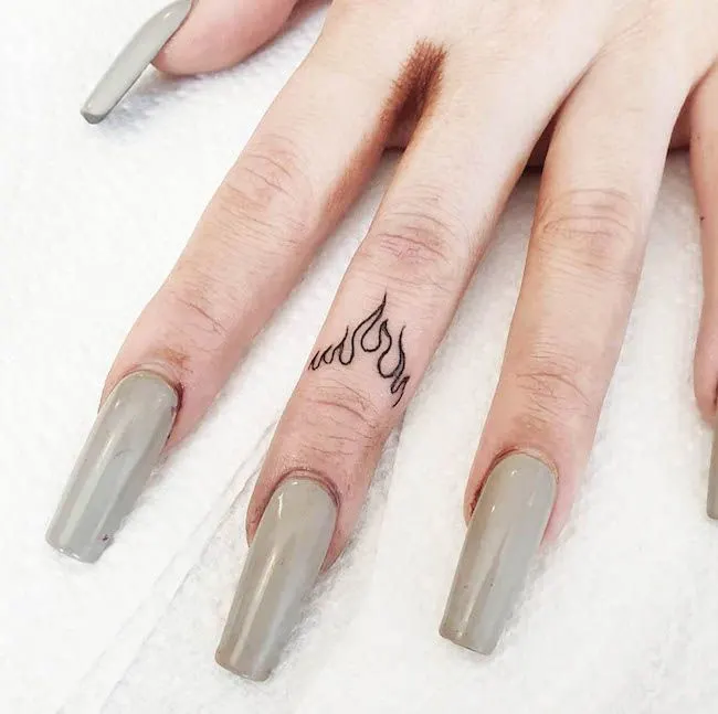 Un tatuaggio con fiamma ardente sul dito medio di @emjaytattoo - Idee per tatuaggi da dita delicate