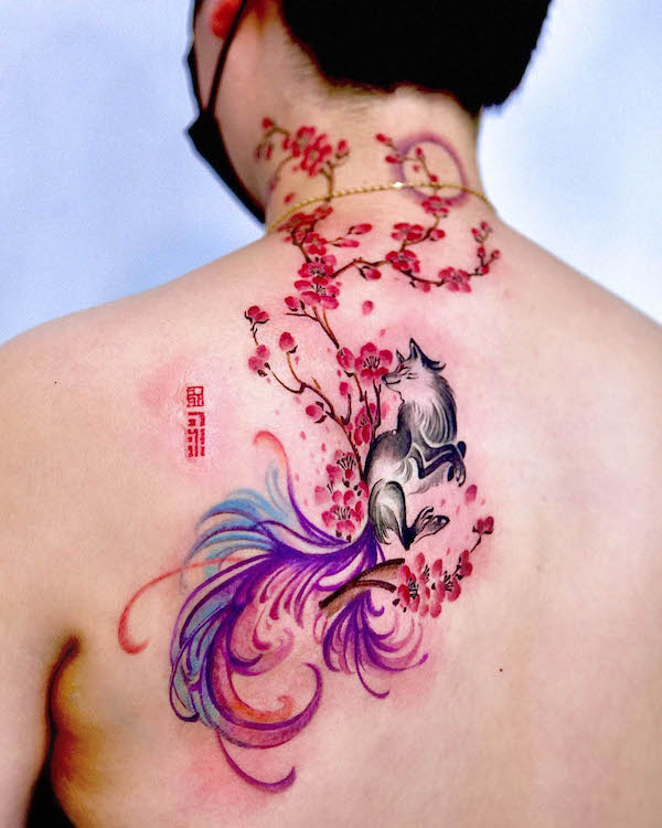 tatuaggio posteriore con volpe kitsune e fiori di ciliegio di @gooka.tattoo