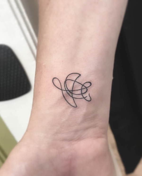 Tartaruga astratta con una linea di tatuaggio sul polso di @claireelise_art