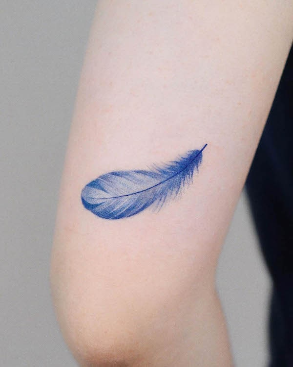 Tatuaggio di piume blu leggero e arioso sul braccio di @zihong_tattoo