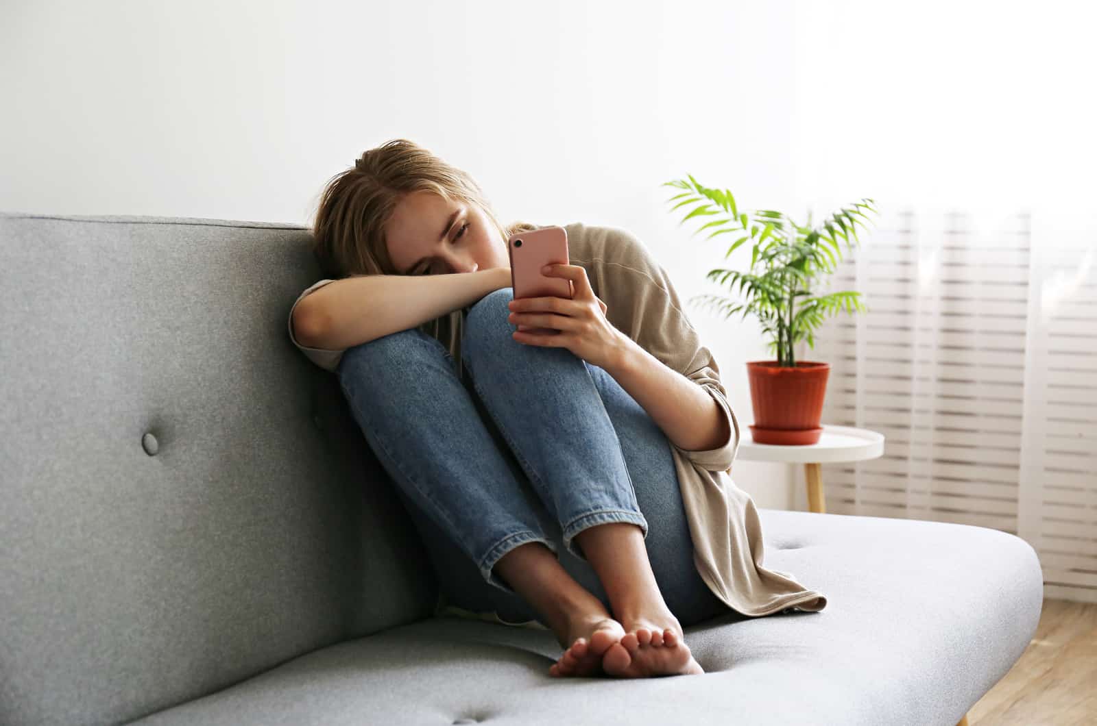 donna triste sul divano al telefono