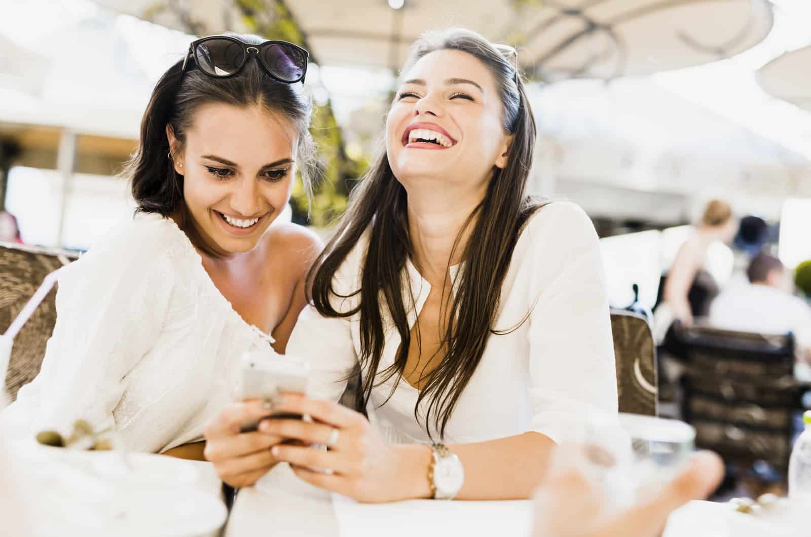 due giovani donne che guardano il telefono ridendo