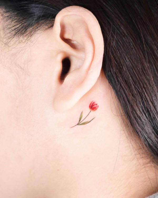 Piccolo fiore dietro l'orecchio tatuaggio a linea fine di @coy.tattoo