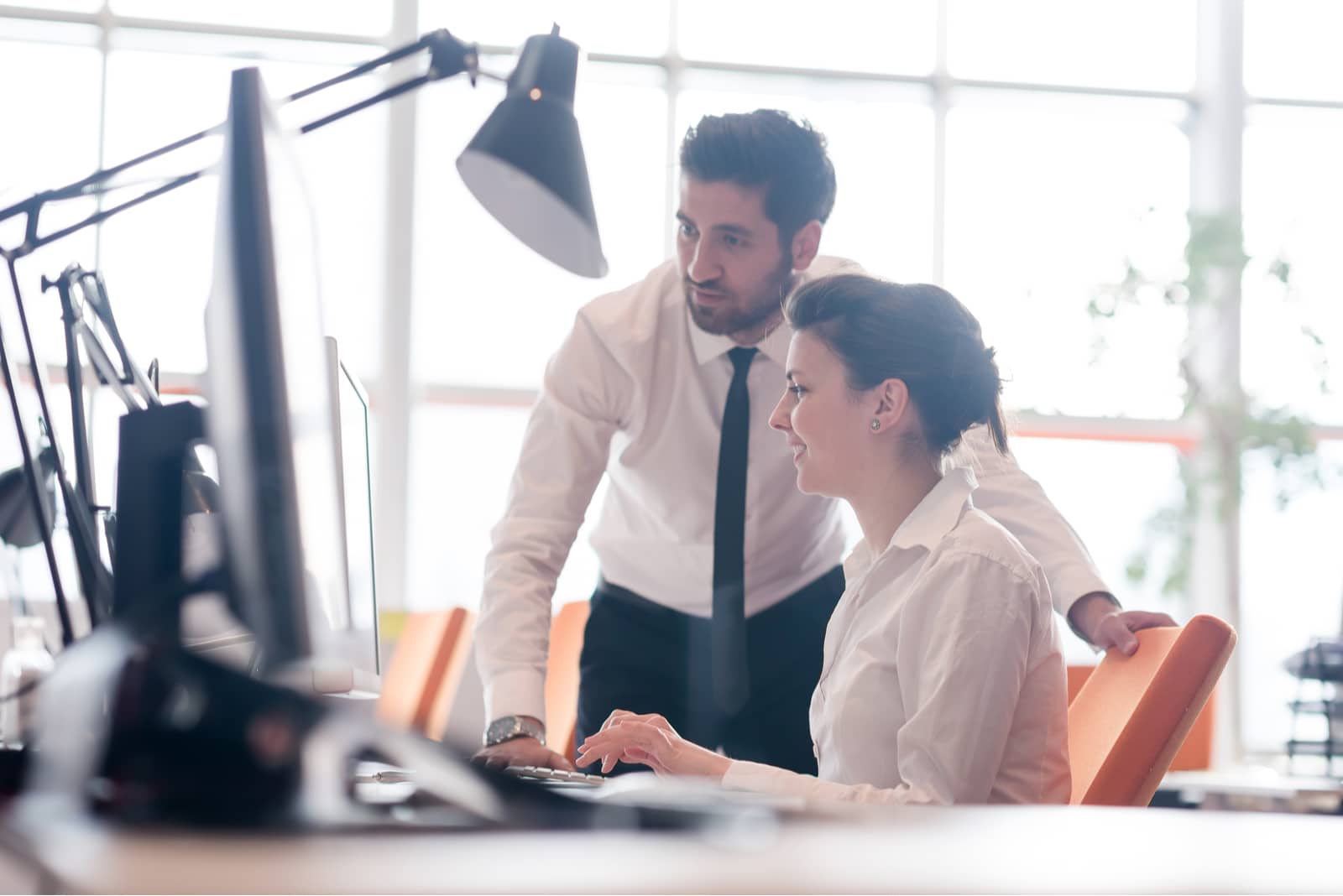 l'uomo si siede e spiega alla donna mentre siede al computer portatile