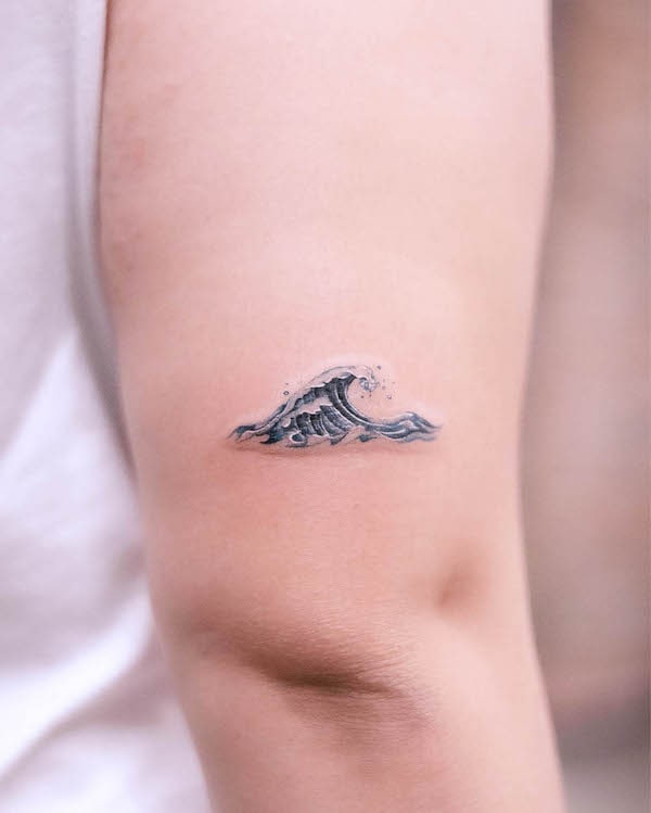 Piccolo tatuaggio a forma di onda blu sul gomito di @handitrip