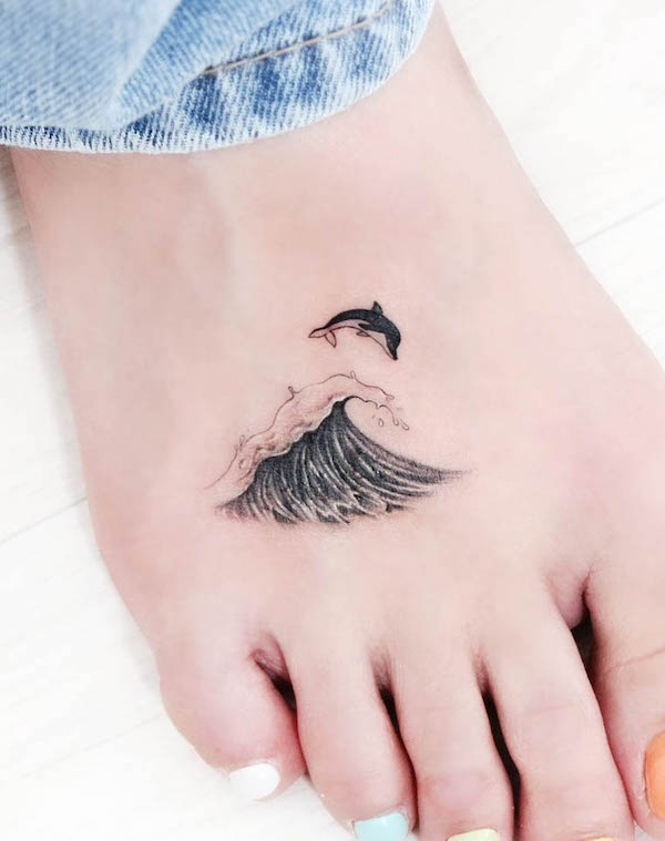 Tatuaggio del piede con delfino e onda di @tatuatore_greem