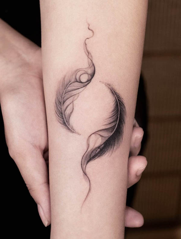 Piume yin e yang sull'avambraccio di @ink.feb24