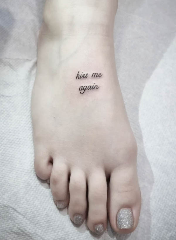 tatuaggio con piede con citazione kiss me again di @buccaneertattoo