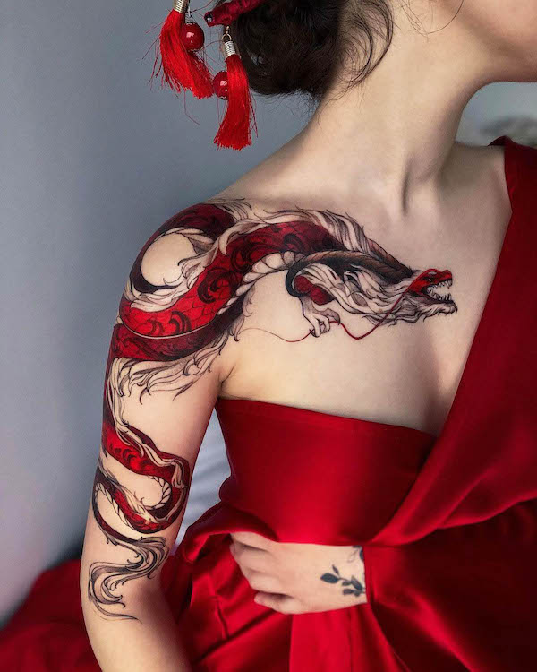 Affascinante drago rosso tatuato sul petto e sulla manica da @tattoo__marka