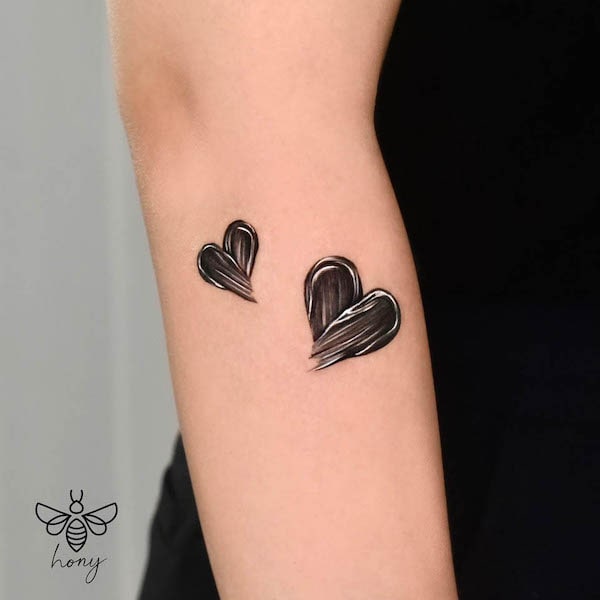 Tatuaggio sull'avambraccio con cuori neri di @_rony_tattoo