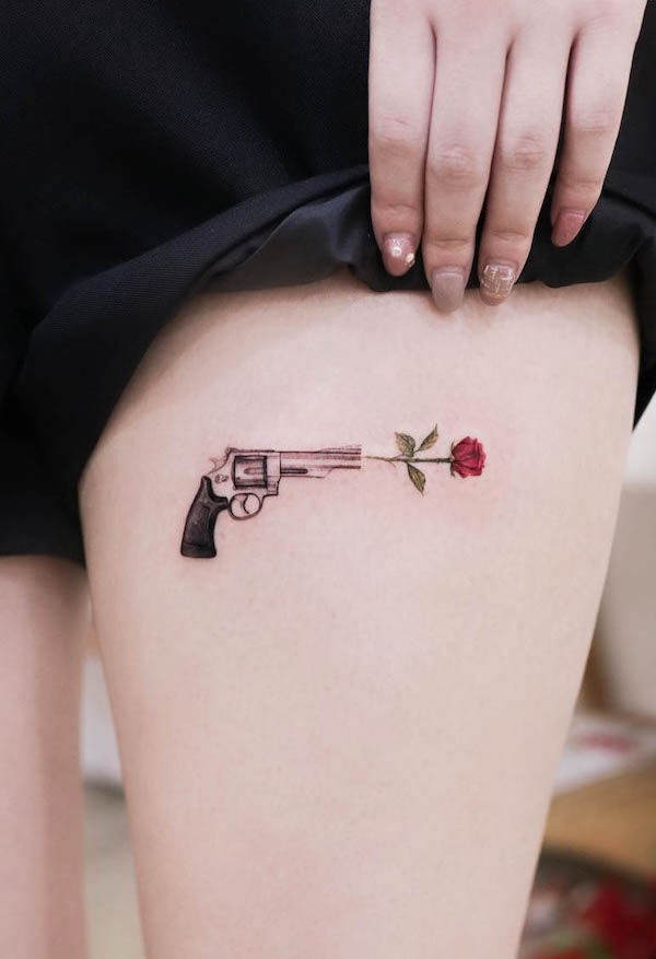 Tatuaggio con pistola e rosa sulla coscia da @tattoo.haneu