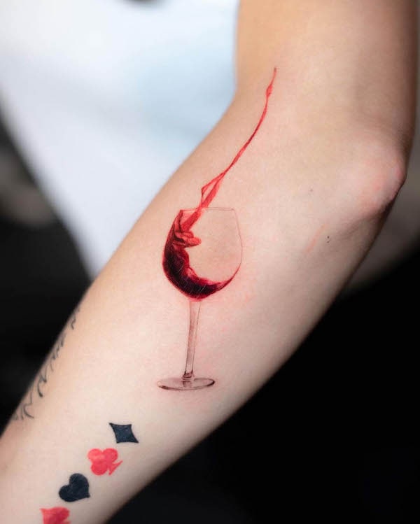 Tatuaggio a braccio con bicchiere di vino di @pelleossa_ink