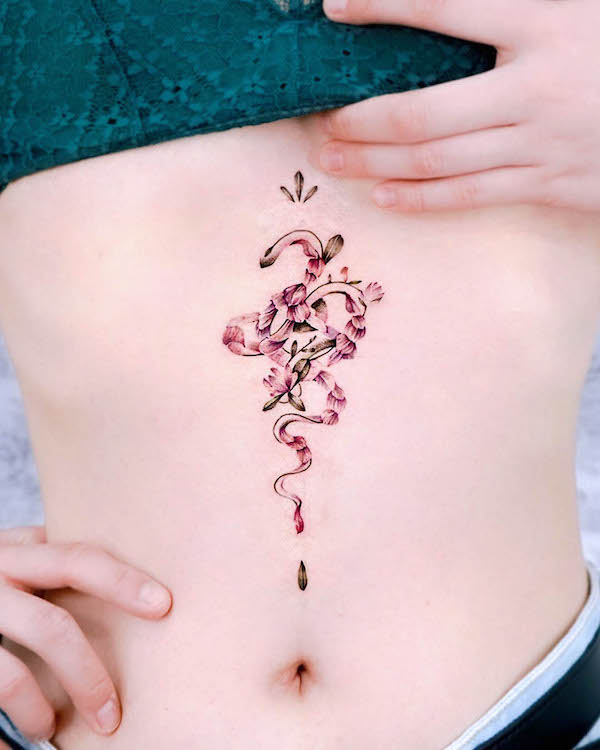 Tatuaggio floreale con serpente sotto il seno da @hwyl.tattoo