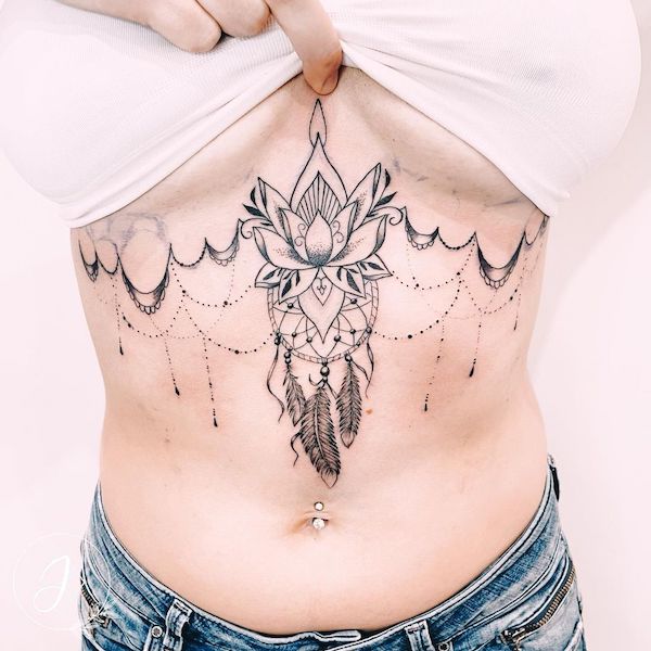 Tatuaggio con loto e acchiappasogni sotto le tette da @julinka.tattoo