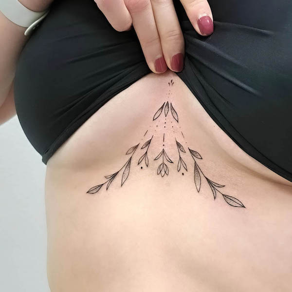 Tatuaggio geometrico di fiori sotto il seno da @inuk.tattoo