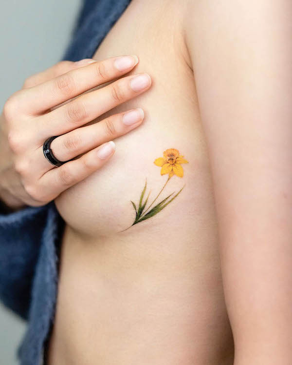 Piccolo fiore giallo tatuaggio laterale di @pokhy_tattoo
