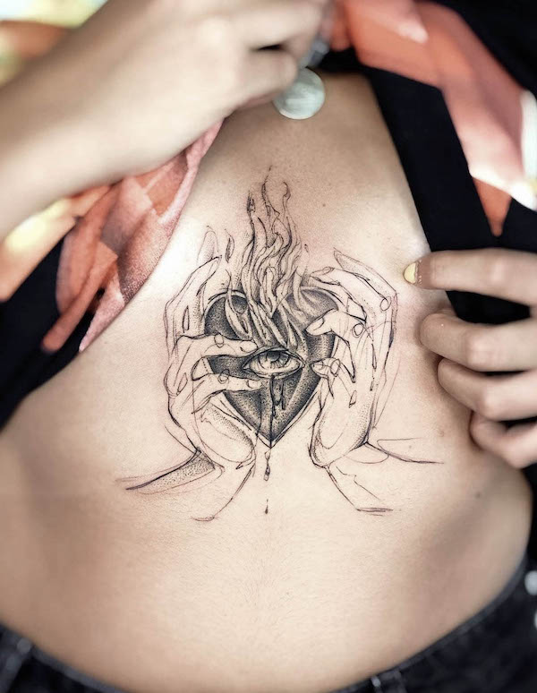 Tatuaggio con cuore sacro bruciante sotto il seno di @paolameyertattoo