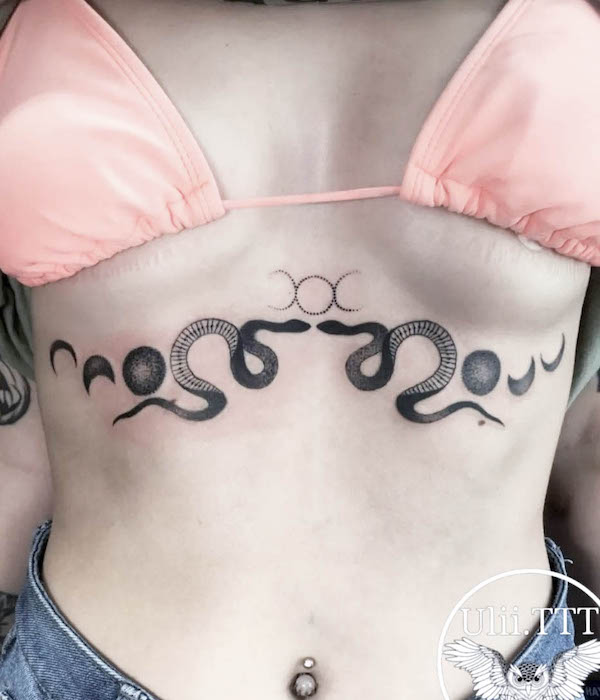 Tatuaggio simmetrico con serpente e luna sotto il seno di @ulii.ttt