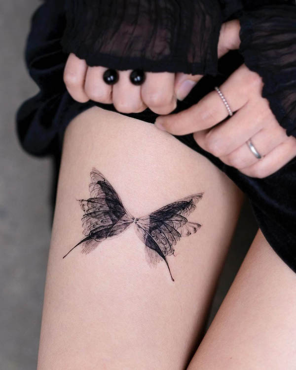 Tatuaggio traslucido sulla coscia con farfalla di @pokhy_tattoo