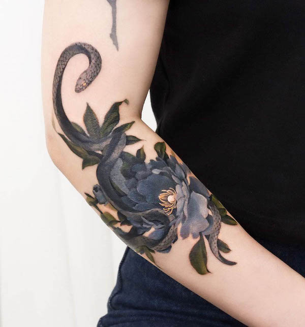 Tatuaggio con serpente e fiori sul gomito di @guppy.flowertattoo
