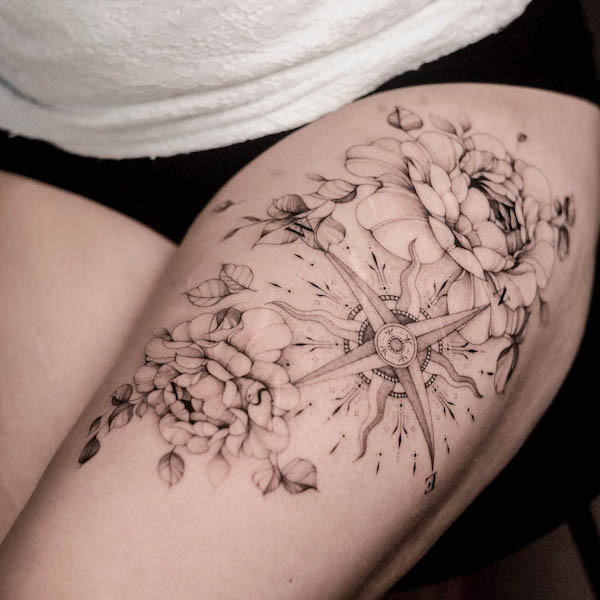 Tatuaggio sulla coscia con bussola e fiori di @dnq.tattoo