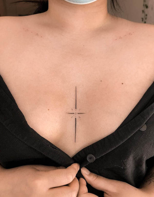 Tatuaggio semplice con croce e stella tra le tette di @shellaeves.art