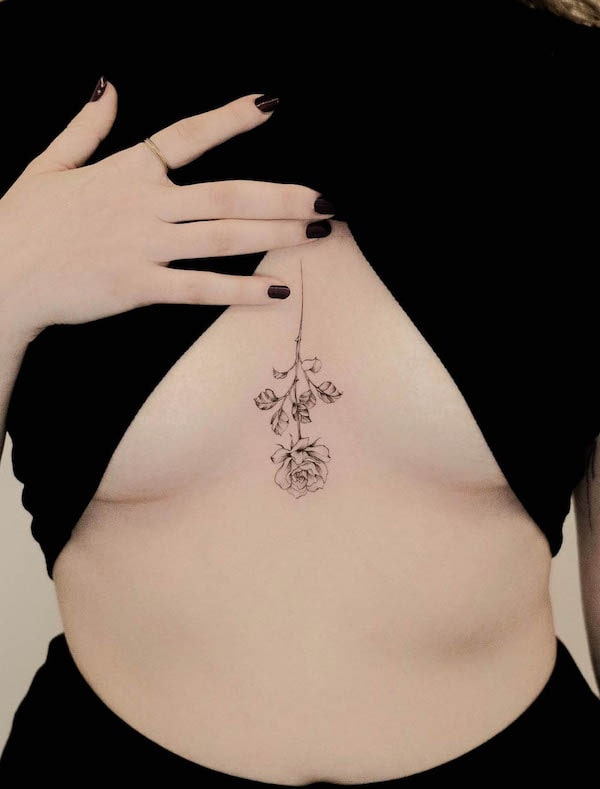 Tatuaggio rosa rovesciata tra le tette da @jk.tattoo