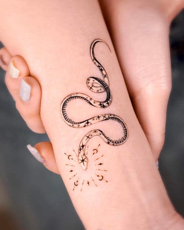 Tatuaggio sull'avambraccio di un piccolo serpente scintillante by @norangtattoo