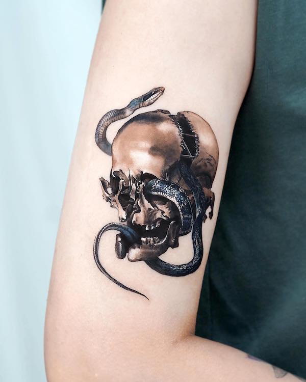 Tatuaggio con serpente e teschio sulla parte superiore del braccio by @stuffie.ink_
