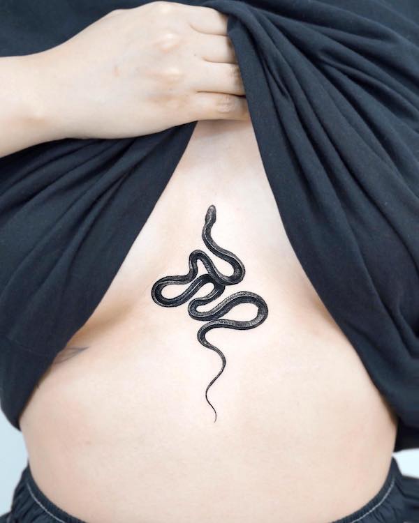 Tatuaggio sul petto con serpente nero by @stuffieink