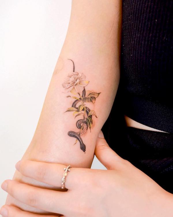 Piccolo tatuaggio a forma di rosa e fiore sulla parte superiore del braccio @sozil_tattoo