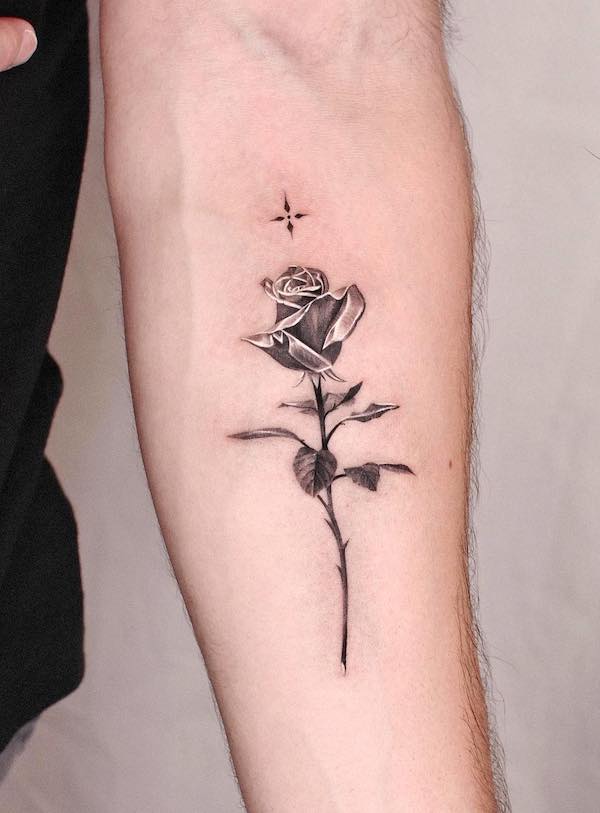 Tatuaggio per braccio con stella e rosa nera metallizzata per donne da @jku_tattoo