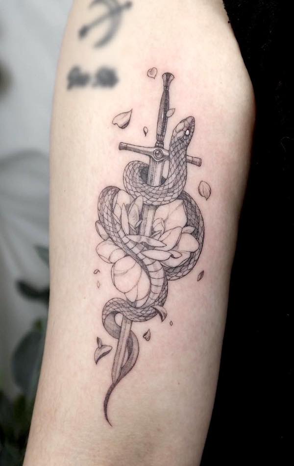 Tatuaggio con serpente e spada sul retro del braccio di @choseung.tat