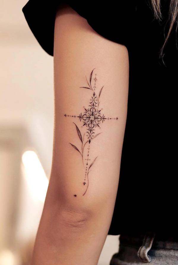 Tatuaggio con croce ornamentale sul retro del braccio di @sukza__art