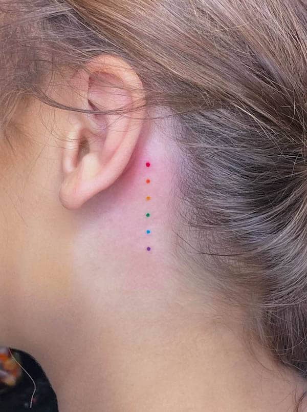 Piccoli punti nei colori dell'arcobaleno dietro l'orecchio di @amandahowtattoo