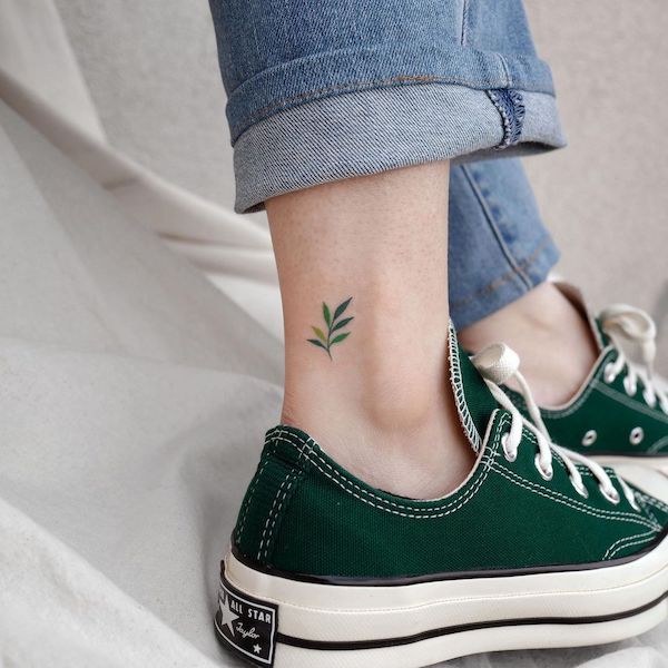 Tatuaggio a forma di piccola foglia sulla caviglia di @eden_tattoo_