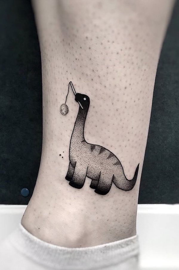 Un divertente tatuaggio a gradiente sulla caviglia di dinosauro di @clinktattooart