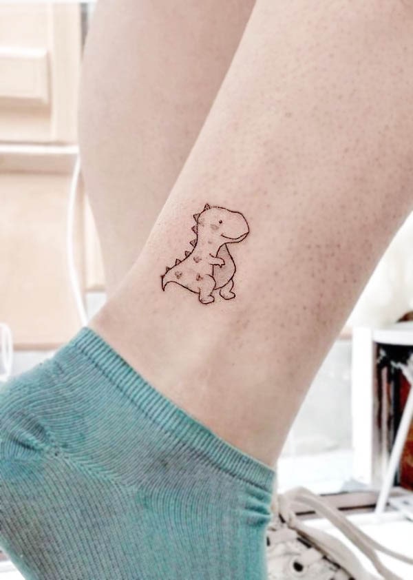 Piccolo dinosauro a cartoni animati sopra la caviglia, tatuaggio di @jskacampos