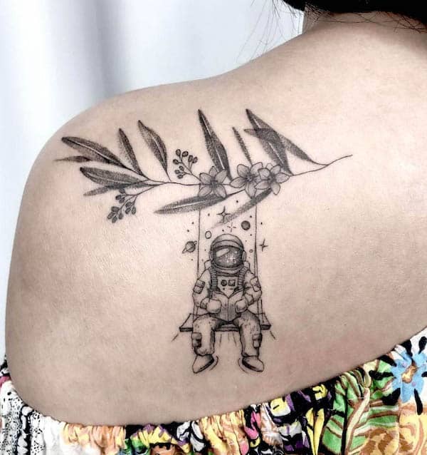 Astronauta su un'altalena floreale tatuaggio sulla spalla di @laridestro_tattoo