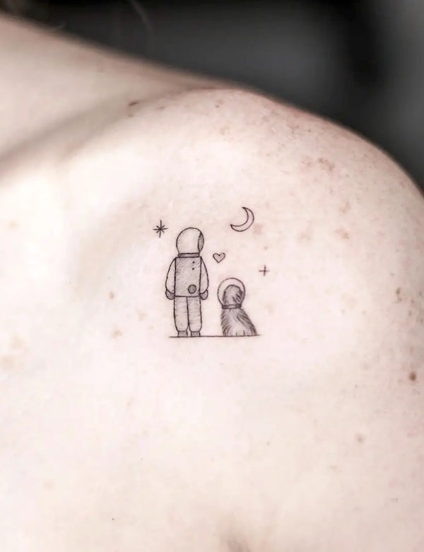 Piccolo astronauta e cane tatuaggio sulla spalla da @jimenaa.home
