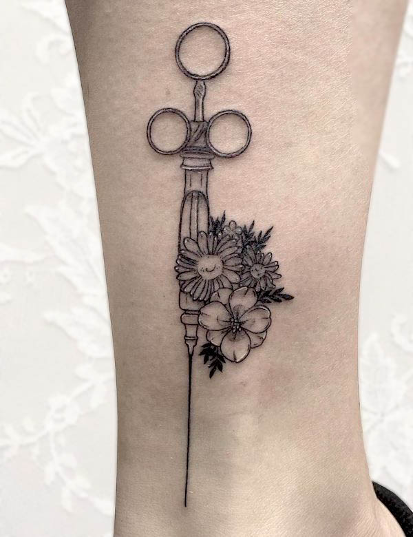 Tatuaggio floreale con siringa di @backtobasicstattoo