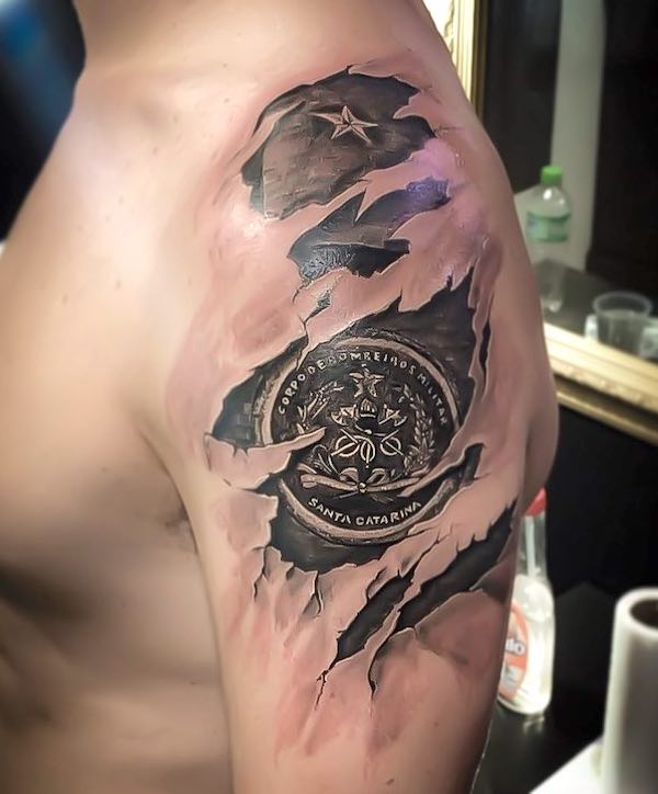 Tatuaggio del distintivo con effetto strappato sulla manica di @luansza