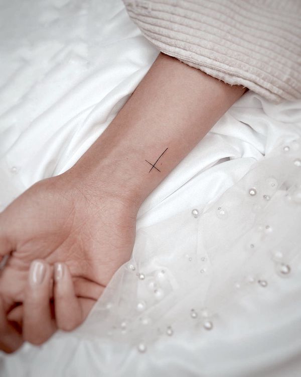 Tatuaggio del polso con croce semplice di @tinytattoos_feathertouch