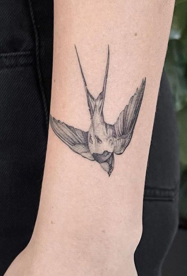 Tatuaggio di uccello nero e grigio sul polso di @jayfineline