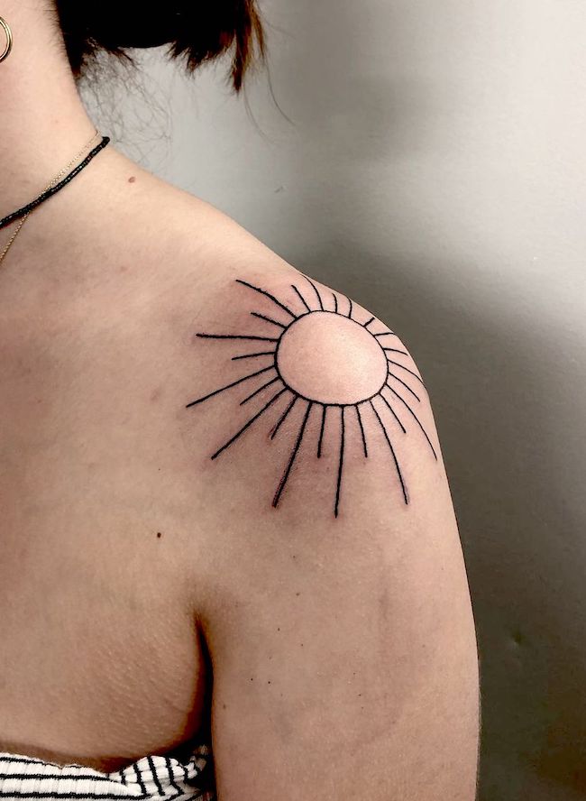 Tatuaggio minimalista del sole sulla spalla di @raevage