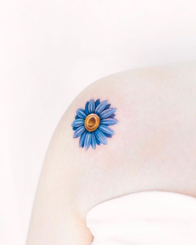 Tatuaggio sulla spalla con margherita blu di @foret_tattoo