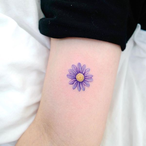 Tatuaggio con margherita viola di @xiso_ink- Tatuaggio con fiore di margherita con significato