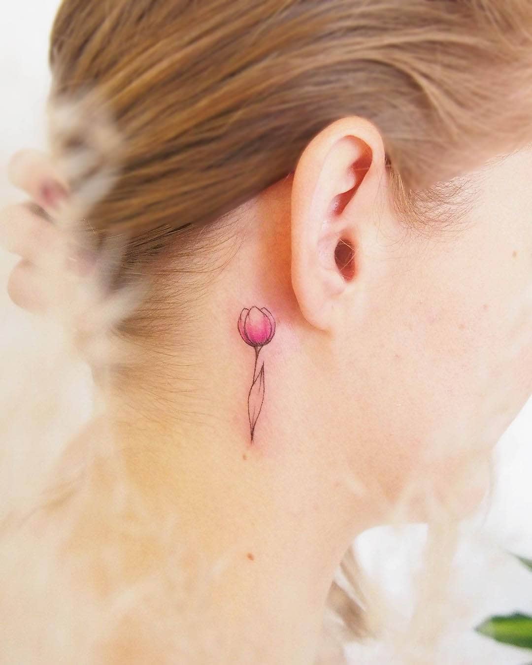 Piccolo tatuaggio a tulipano dietro l'orecchio di @deni_teckuje