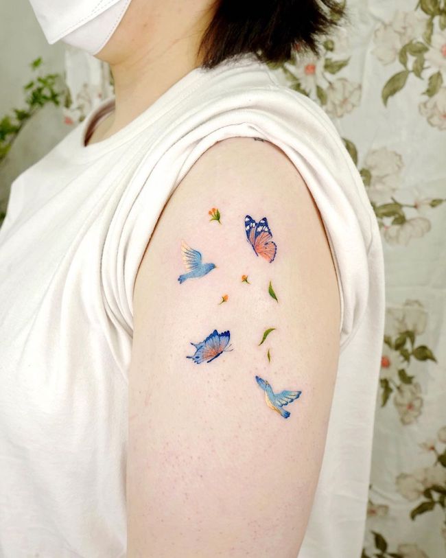 Tatuaggio a manica colorata con farfalle e uccelli di @ovenlee.tattoo