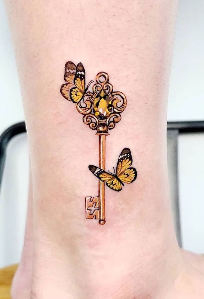 Tatuaggio alla caviglia con farfalla e chiave d'oro di @tattooist_violet